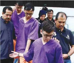  ??  ?? Lee (front) and his two assistants being led away after court proceeding­s yesterday.