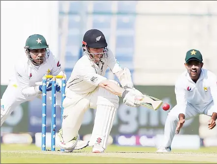  ??  ?? New Zealand captain Kane Williamson (center), plays a shot as Pakistani captain and wicketkeep­er Sarfraz Ahmed (left), and teammate Asad Shafiq (right), look on during the first day of the third and final Test cricket match between Pakistan and New Zealand at the Sheikh Zayed Internatio­nal CricketSta­dium in Abu Dhabi on Dec 3. (AFP)