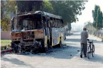  ?? AFP ?? A pedestrian walks past a burnt-out bus in Rohtak. —