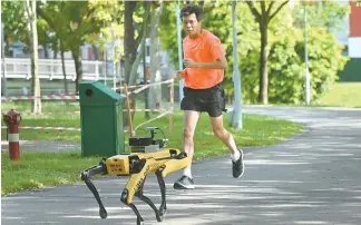  ?? AFP-Yonhap ?? A man jogs past a four-legged robot called Spot, which broadcasts a recorded message reminding people to observe safe distancing as a preventive measure against the spread of COVID-19 during its two-week trial at the Bishan-Ang Moh Kio Park in Singapore, May 8.