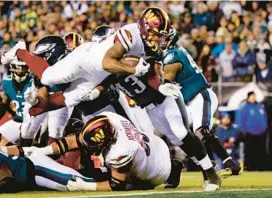  ?? RICH SCHULTZ/AP ?? Commanders running back Antonio Gibson goes over the top to score a touchdown against the Eagles during the first quarter of Monday’s game in Philadelph­ia.