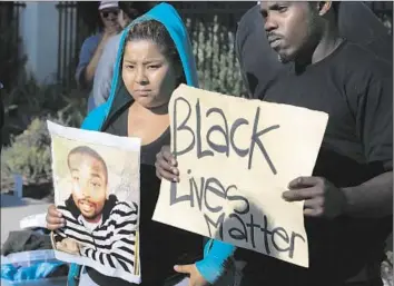  ?? Mark Boster Los Angeles Times ?? ACTIVISTS HOLD photos of Ezell Ford in protesting at Mayor Eric Garcetti’s home. The Los Angeles Police Commission will consider the shooting as well as the officers’ actions leading up to the incident.