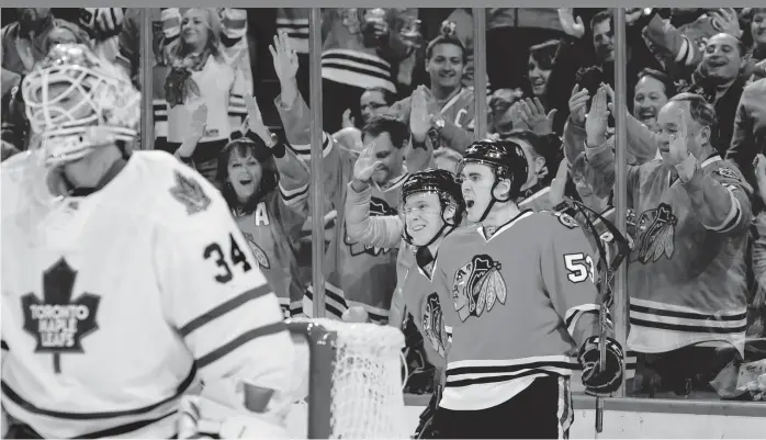  ?? | BILL SMITH/ GETTY IMAGES ?? Blackhawks left wing Brandon Mashinter ( 53) celebrates his goal with teammate Dennis Rasmussen behind Maple Leafs goalie James Reimer in the first period Monday at the United Center.