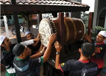  ?? ?? Committee members put the beduk in place in preparatio­n for the start of the fasting month. — Bernama photo