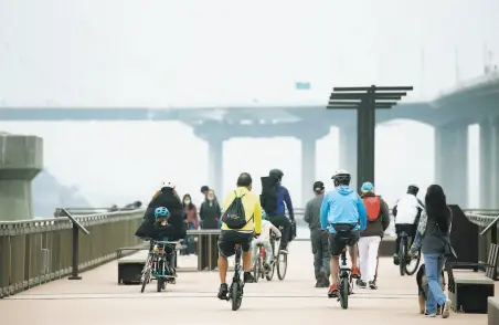  ?? Paul Chinn / The Chronicle ?? Visitors explore the new pier at Judge John Sutter Regional Shoreline with the roar of Bay Bridge traffic overhead in Oakland.