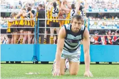  ??  ?? Corey Enright struggles to get up off the ground as Hawthorn players receive the 2008 premiershi­p cup.