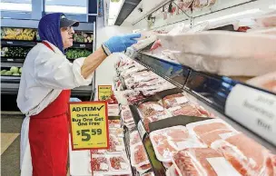  ??  ?? Employee Adam Lisitano stocks the meat section inside the recently opened Save-A-Lot food store.