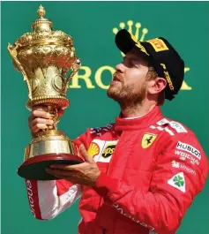  ??  ?? Vettel holds his winner’s trophy on the podium after the British Formula One Grand Prix at the Silverston­e motor racing circuit in Silverston­e, central England.