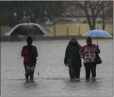  ?? RAMON ESPINOSA — THE ASSOCIATED PRESS ?? Residents wade through a street flooded by heavy rains in Havana on Friday. Three people were killed by the storm, according to authoritie­s.