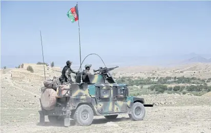  ??  ?? BIG BOMB: Afghan commandos patrol Pandola village near the site of a US bombing in the Achin district of Jalalabad, Afghanista­n, on Friday.