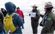  ??  ?? New York City Park Rangers Adriana Caminero (right) and A. Duran (centre) explain to wildlife enthusiast­s the types of seals they’ll be looking for near Orchard Beach in New York City.