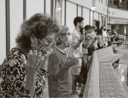  ?? Photos by Ronald Cortes / Contributo­r ?? Gloria Belmares prays with others during a Mass at St. Pius X Catholic Church. Wearing masks is encouraged, but some don’t.