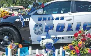  ?? – AFP ?? TRIBUTE: Flowers and candles adorn a memorial outside the Dallas Police Headquarte­rs.