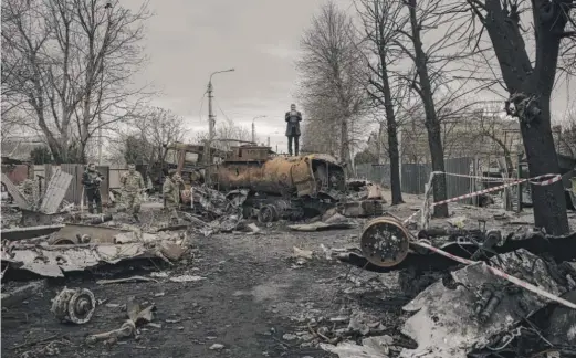  ?? FELIPE DANA/AP ?? A journalist stands atop a destroyed vehicle after fights between Russian and Ukrainian forces in Bucha, on the outskirts of Kyiv, Ukraine, Wednesday. Ukrainian leaders have encouraged journalist­s to document what is happening.