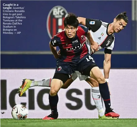  ?? — ap ?? caught in a tangle: Juventus’ cristiano Ronaldo tries to get past Bologna’s takehiro tomiyasu at the Renato dall’ara stadium in Bologna on Monday.