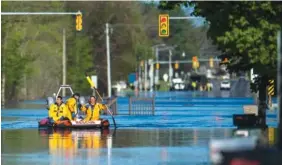  ?? KATY KILDEE/MIDLAND DAILY NEWS VIA AP ?? A search and rescue boat is deployed as Saginaw Road is closed at Drake due to water over the road while floodwater rises in Midland, Mich., on Wednesday