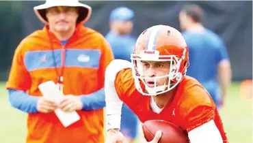  ??  ?? Florida quarterbac­k Feleipe Franks, right, runs with the football as head coach Dan Mullen watches during practice. (Photo by Brad Mcclenny, The Gainesvill­e Sun, AP file)