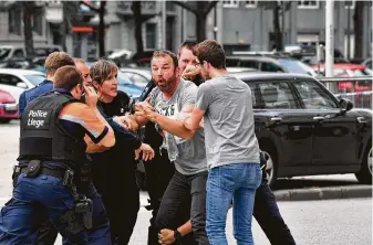  ?? Geert Vanden Wijngaert / Associated Press ?? Police try to calm a man Tuesday after an attack in Liege, Belgium. A knife-wielding inmate on leave stabbed two officers, stole their guns and killed them and a teacher before being shot down.