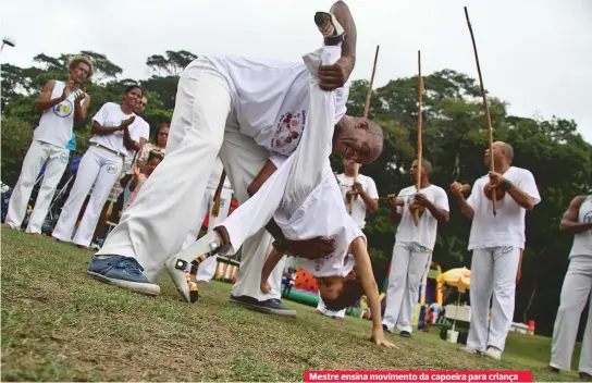  ??  ?? Mestre ensina movimento da capoeira para criança