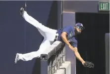  ?? Sean M. Haffey / Getty Images ?? Tampa Bay’s Manuel Margot, a former Padres outfielder, catches a foul ball as he crashes over the wall in San Diego.