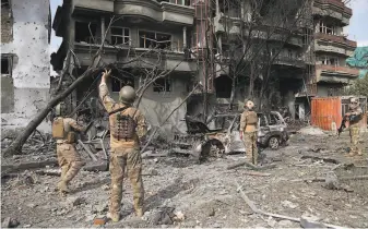  ?? Rahmat Gul / Associated Press ?? Security forces examine damage from a bombing and gunbattle in the Afghan capital of Kabul. Sunday’s attack, which lasted hours, targeted the Green Trend party headquarte­rs.