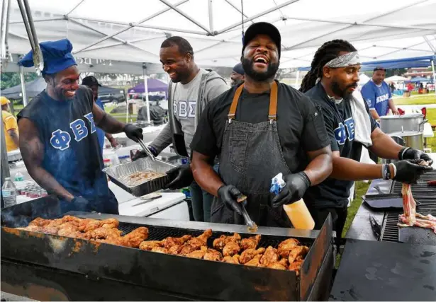  ?? PHOTOS BY JOHN TLUMACKI/GLOBE STAFF ?? Brian Alleyne and fellow members of the Phi Beta Sigma fraternity grilled food for people at the picnic in Franklin Park.