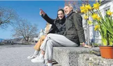  ?? FOTO: FELIX KÄSTLE/DPA ?? Zwei Studentinn­en sitzen neben ihren gerade eben gekauften Osterglock­en an der Uferpromen­ade in Überlingen.