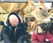  ?? ANN DAVIDSON ?? Denis Paradis with a young farmhand chat inside the dairy barn at Ferme Missiska in Saint-armand .