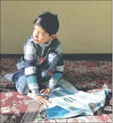  ??  ?? Murtaza with the jersey that was given and signed by Barcelona star Lionel Messi at his house in Kabul, Afghanista­n. — Reuters photo