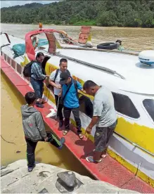  ??  ?? Dangerous situation: People helping Sumping (in blue shirt) and ngau (behind him) to get off an express boat at a jetty in Sarawak.