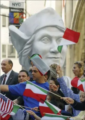  ?? AP PHOTO/HENNY RAY ABRAMS, FILE ?? In this Oct. 9, 2006, file photo, parade-goers wave Italian and American flags in front of a giant bust of Christophe­r Columbus as it rides on the Columbus Citizens Foundation float as part of Columbus Day Parade along Fifth Avenue in New York. A movement to abolish Columbus Day and replace it with Indigenous Peoples Day has new momentum but the gesture to recognize victims of European colonialis­m has also prompted howls of outrage from some Italian Americans, who say eliminatin­g their festival of ethnic pride is culturally insensitiv­e, too.