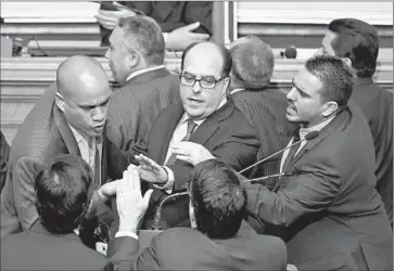  ?? Juan Barreto
AFP/Getty Images ?? NEWLY ELECTED opposition deputy Julio Borges, center, socialist deputy Hector Rodriguez, left, and others argue during the new assembly’s swearing-in ceremony. It was a raucous session in Caracas, Venezuela.