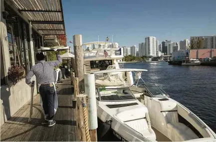  ??  ?? Garçom de novo restaurant­e à beira do rio Miami; clientes podem atracar seus iates e desembarca­r para consumir