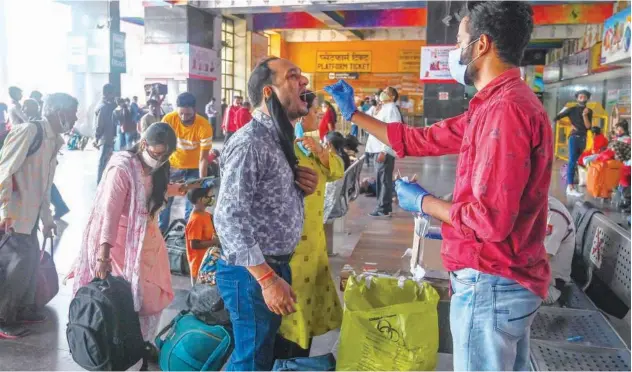  ?? Agence France-presse ?? ↑
A medical worker takes a swab sample from a man to test for COVID-19 at a railway station in New Delhi on Tuesday.