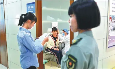  ?? GAO WEI / FOR CHINA DAILY ?? Teenagers have their ears checked during the extensive physical examinatio­n process for military recruits in Kunming, Yunnan province, on Monday. Candidates must pass every item on the checklist to be accepted.
