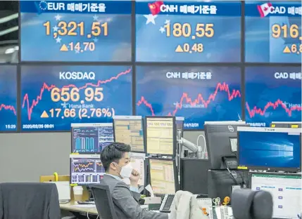  ?? Jean Chung, © The New York Times Co. ?? A trader wears a mask inside a stock exchange area at Hana Bank in Seoul, South Korea, on Tuesday. Americans should brace for the likelihood that the coronaviru­s will spread to communitie­s in the United States, the national Centers for Disease Control and Prevention has warned. In less than a week, the S&P 500 has shed 7.6% of its value.