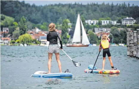  ?? FOTO: FELIX KÄSTLE/DPA ?? Stand-up-paddlerinn­en auf dem Bodensee zwischen der Insel Reichenau und Allensbach: Der Bodensee ist auch in diesem Jahr eines der beliebtest­en Urlaubszie­le im Südwesten.