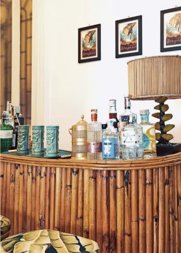  ??  ?? sopra Il mobile bar anni ’50 in stile “hawaiano” è uno dei pochi arredi che arriva dal precedente appartamen­to di Paride Vitale. Alla parete, stampe eseguite a mano realizzate in occasione della personale di Maurizio Cattelan alla Kunsthaus di Bregenz (2008). a sinistra In una delle camere da letto, lo spazio è reso scenografi­co dal contrasto tra la parete dipinta in rosso e le altre, rivestite in carta da parati dal motivo classico (Marly, Colony) come anche l’armadio, che si mimetizza. Poltroncin­a e console vintage. Nel corridoio: lampada Jobby the cat, Seletti, design Studio Job.