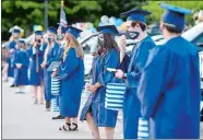  ?? SARAH GORDON/THE DAY ?? Graduates stand in front of their families’ cars Friday during Ledyard High School’s drive-in graduation.