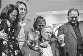  ??  ?? Gov. Greg Abbott, center, joined Sutherland Springs shooting survivors in prayer during the public dedication service for their new church building.