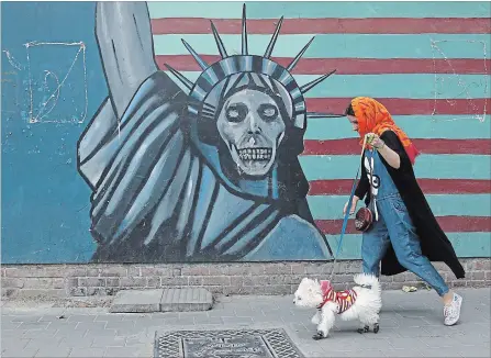  ?? VAHID SALEMI
THE ASSOCIATED PRESS ?? A woman walks her dog past an anti-U.S. mural painted on the wall of the former American embassy in Tehran on Tuesday.