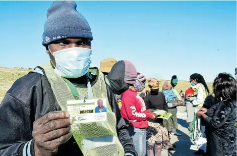  ?? Picture: EUGENE COETZEE ?? GOOD TO GO: Authorised recycler Emmanuel Tenga receives his identity card and reflective bib from Nelson Mandela Bay municipal officials at the Arlington tip