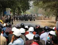  ??  ?? Protesters stand behind a makeshift barricade Monday in Naypyitaw, Burma, as police prepare to fire tear gas.
(AP)