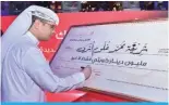  ?? ?? Mohammad Al-Qattan signs the check for the winner of the semi-annual prize in the Al-Danah Millionair­e draw.