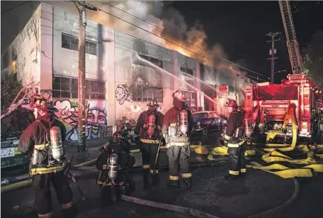  ?? Photograph­s by David Butow Redux / For The Times ?? FIREFIGHTE­RS BATTLE a blaze on 31st Avenue in Oakland. Officials said it could take two days to finish searching for missing people.