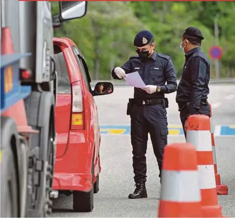  ?? PIC BY AIZUDDIN SAAD ?? Policemen checking documents for inter-state travel at the Gombak toll plaza yesterday.