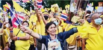  ?? — AFP photo ?? A royalist supporter waves flags while holding a small dog during a rally to show support for the Thai royal establishm­ent in Bangkok.