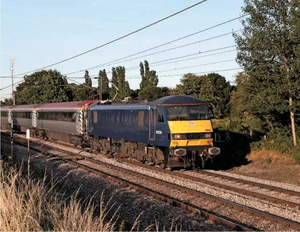  ?? ANTONY GUPPY. ?? DB Cargo 90034, on hire to Abellio Greater Anglia, races through Ardleigh (between Manningtre­e and Colchester) with the 1800 Norwich-London Liverpool Street on August 15. Class 90s and Mk 3s were introduced in 2004, and will be replaced in 2019. The...