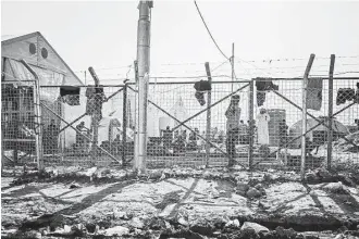  ?? Alice Martins / Associated Press ?? Men wait behind a fenced area where they are interrogat­ed before being allowed to stay at the Dibaga Camp for displaced people last week in Hajj Ali, northern Iraq.