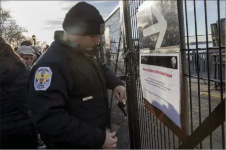  ?? MARY ALTAFFER — THE ASSOCIATED PRESS ?? A United States Park Police officer posts a sign informing of closings of the Statue of Liberty and Ellis Island at an entrance to a ferry Jan. 20 in New York “due to a lack of appropriat­ions.”